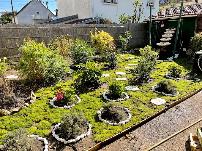 Massifs plantés entourés de bordures en galets dans un jardin de ville