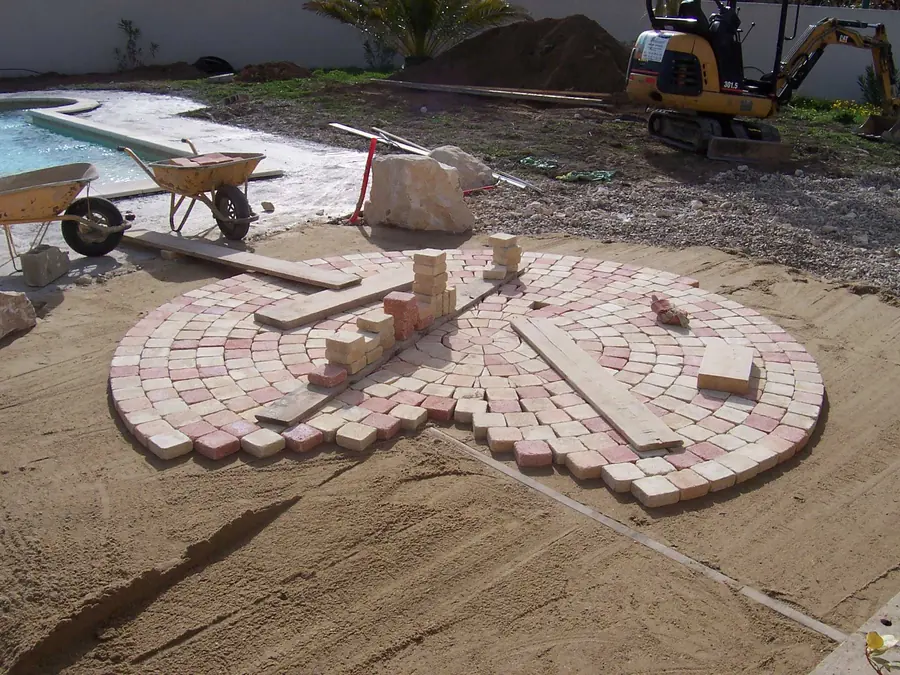 Pose de pavés en rosace sur lit de sable pendant un chantier